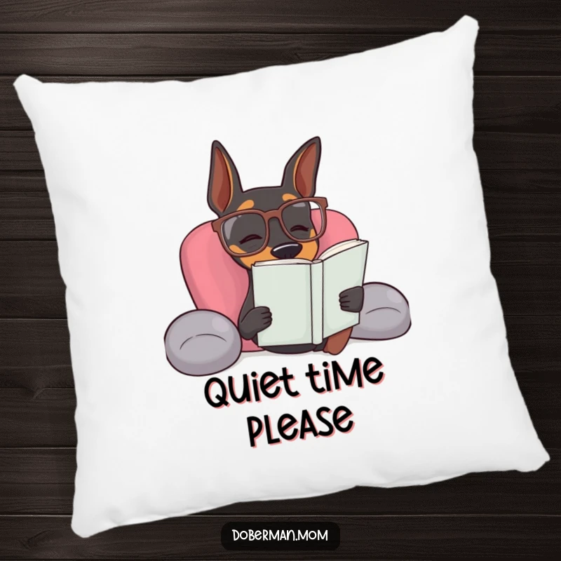Funny Doberman dog wearing reading glasses looking relaxed on a plush, humorous pillow.