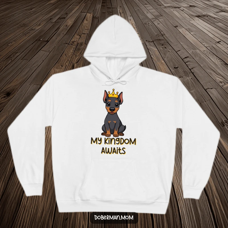 Funny Doberman dog wearing a tiny crown, sitting attentively, featured on a cozy hoodie, perfect for royal dog lovers.