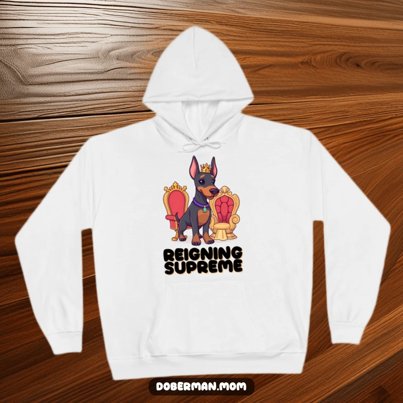 Funny Doberman hoodie depicting a proud Doberman wearing a tiny crown beside a miniature throne, embodying noble comfort.